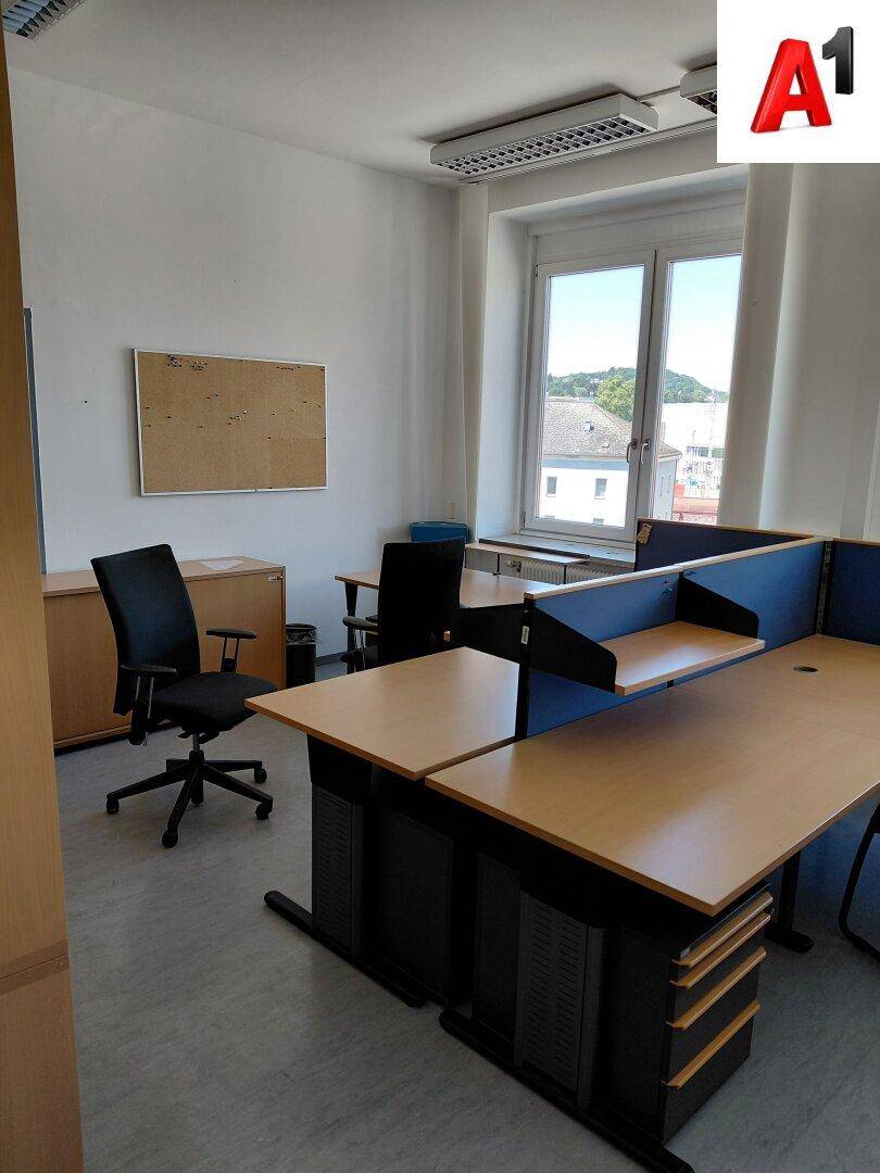 Geräumiges Büro mit mehreren Arbeitsplätzen, Holzschreibtischen und Blick nach draußen.