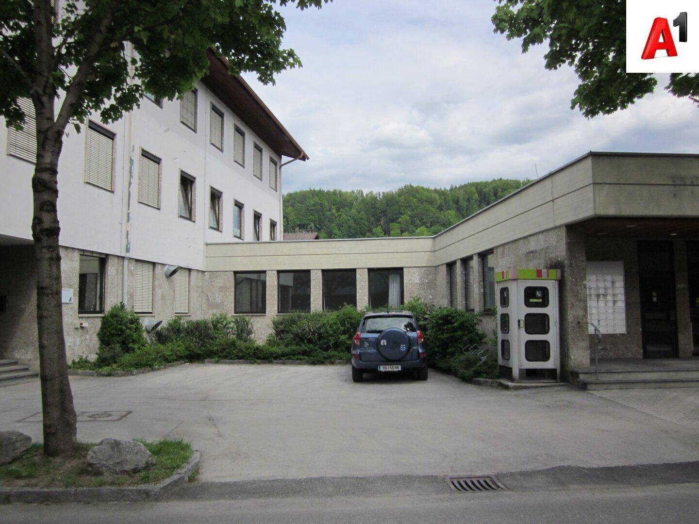 Seitenansicht des Gebäudes mit einem Parkplatz und umliegender grüner Landschaft.