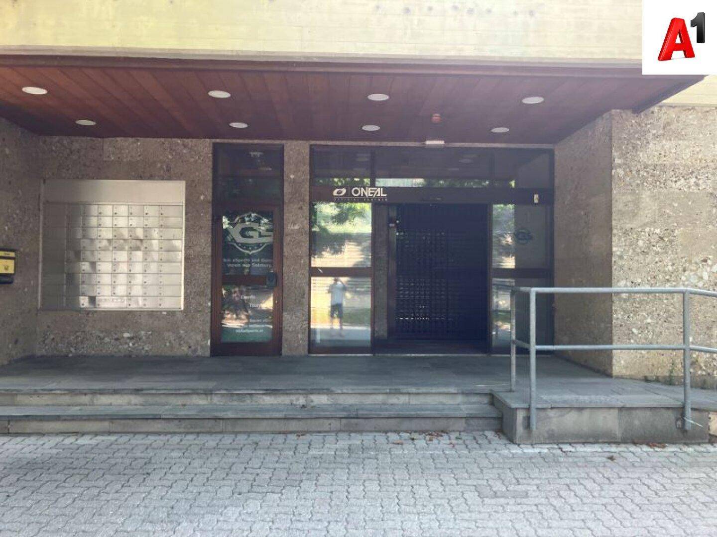 Haupteingang mit Briefkästen, Glastüren und einer kleinen Rampe für den Zugang.