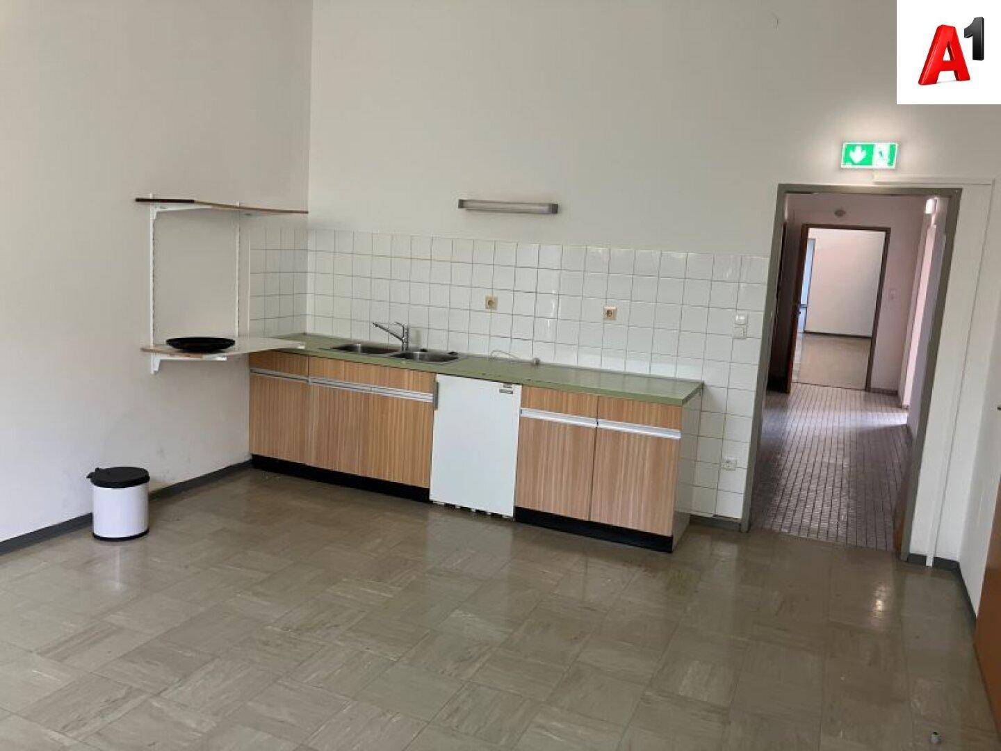 Kleine Küche mit älteren Holzschränken, Spüle und einem Geschirrspüler.