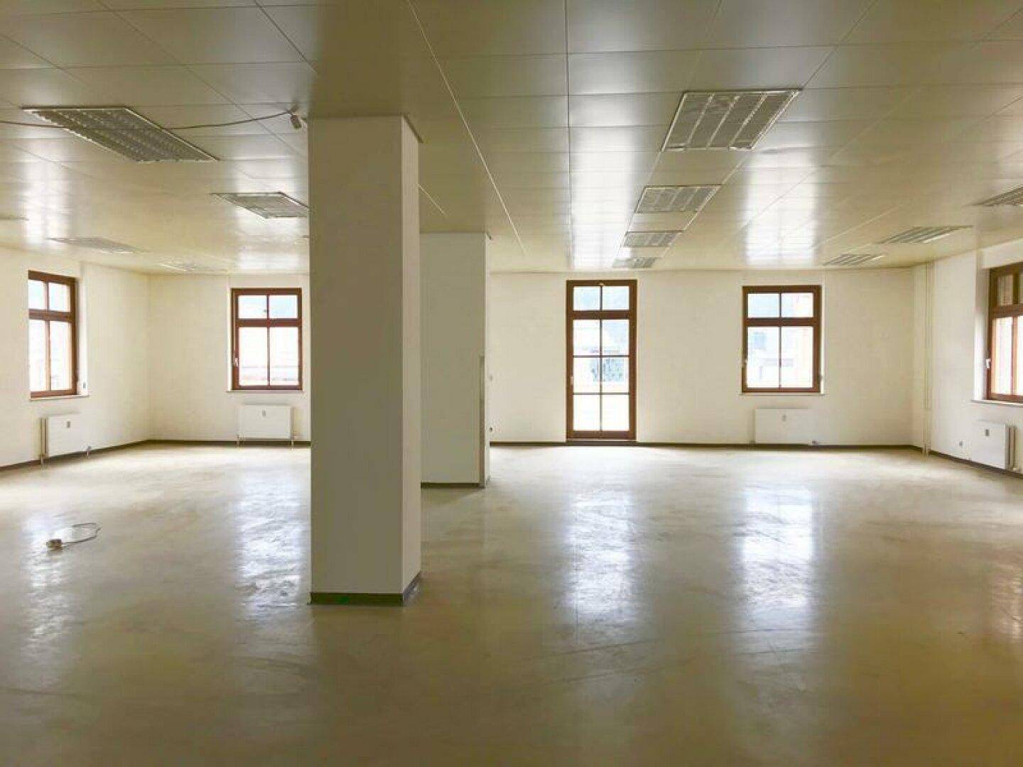 Heller und geräumiger Büroraum mit Säulen, vielen Fenstern und einem funktionalen Deckenraster.