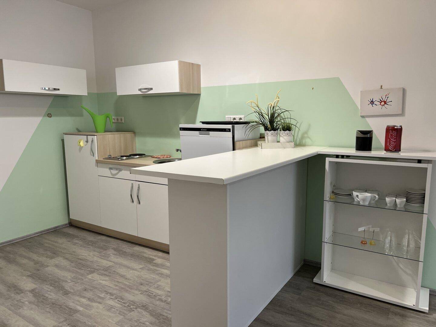Funktionale Küchenzeile mit weißer Arbeitsplatte, Spülmaschine und integriertem Regal, ideal für kleine Räume.