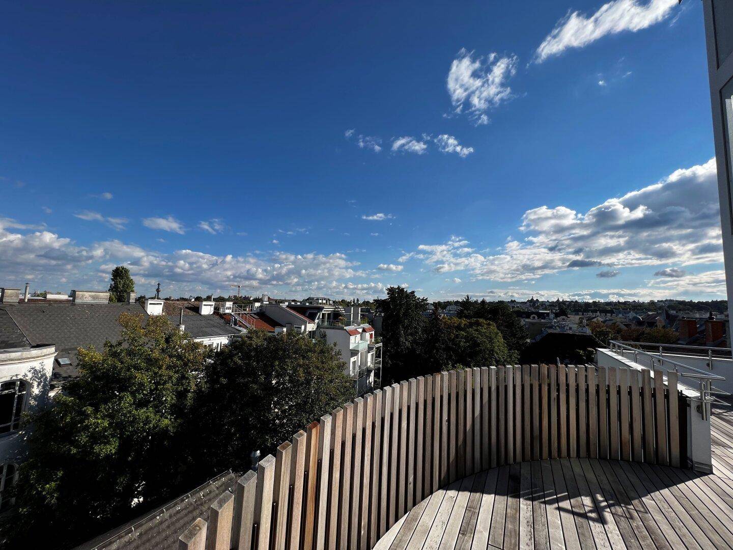 Dachterrasse mit Holzboden und einer modernen Holzumzäunung, die Privatsphäre bietet.