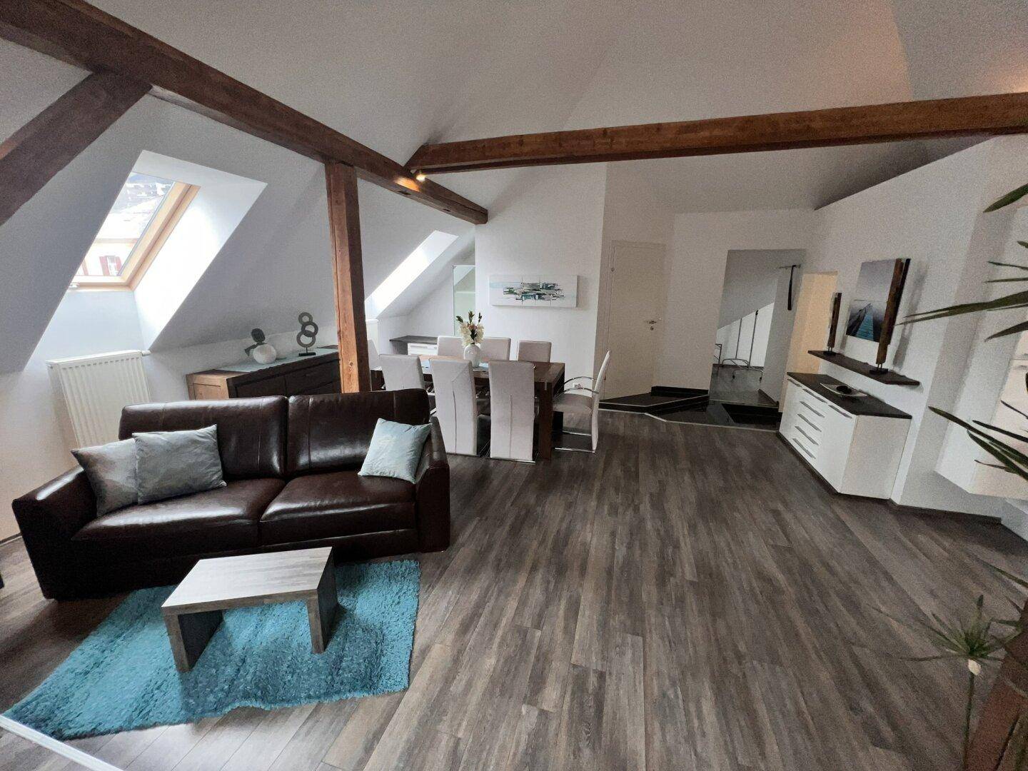 Gemütlicher Wohnbereich im Dachgeschoss mit Ledersofa, Couchtisch und Blick auf die Dachfenster.