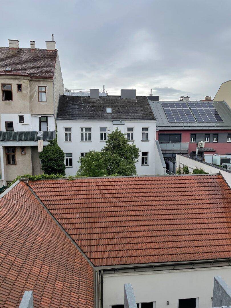Blick über die Dächer von Wohngebäuden mit traditionellen Ziegeldächern und Solaranlagen.
