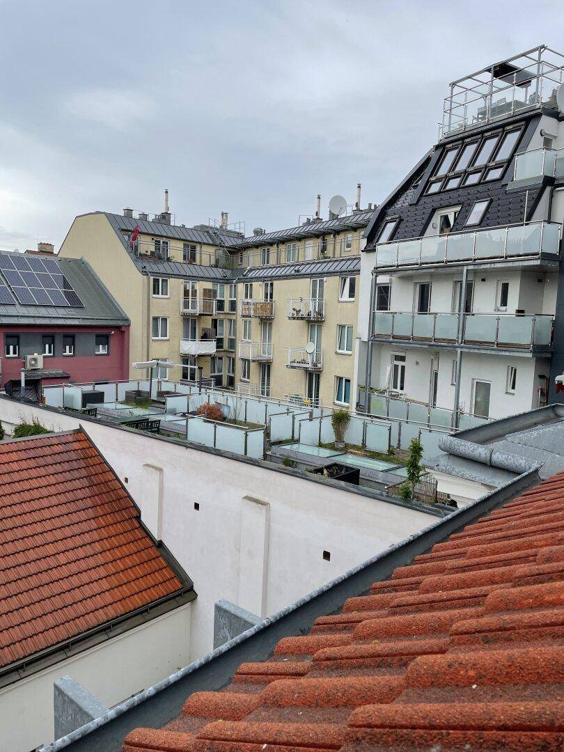 Blick über Dächer von Wohngebäuden mit Balkonen und Dachterrassen unter bewölktem Himmel.