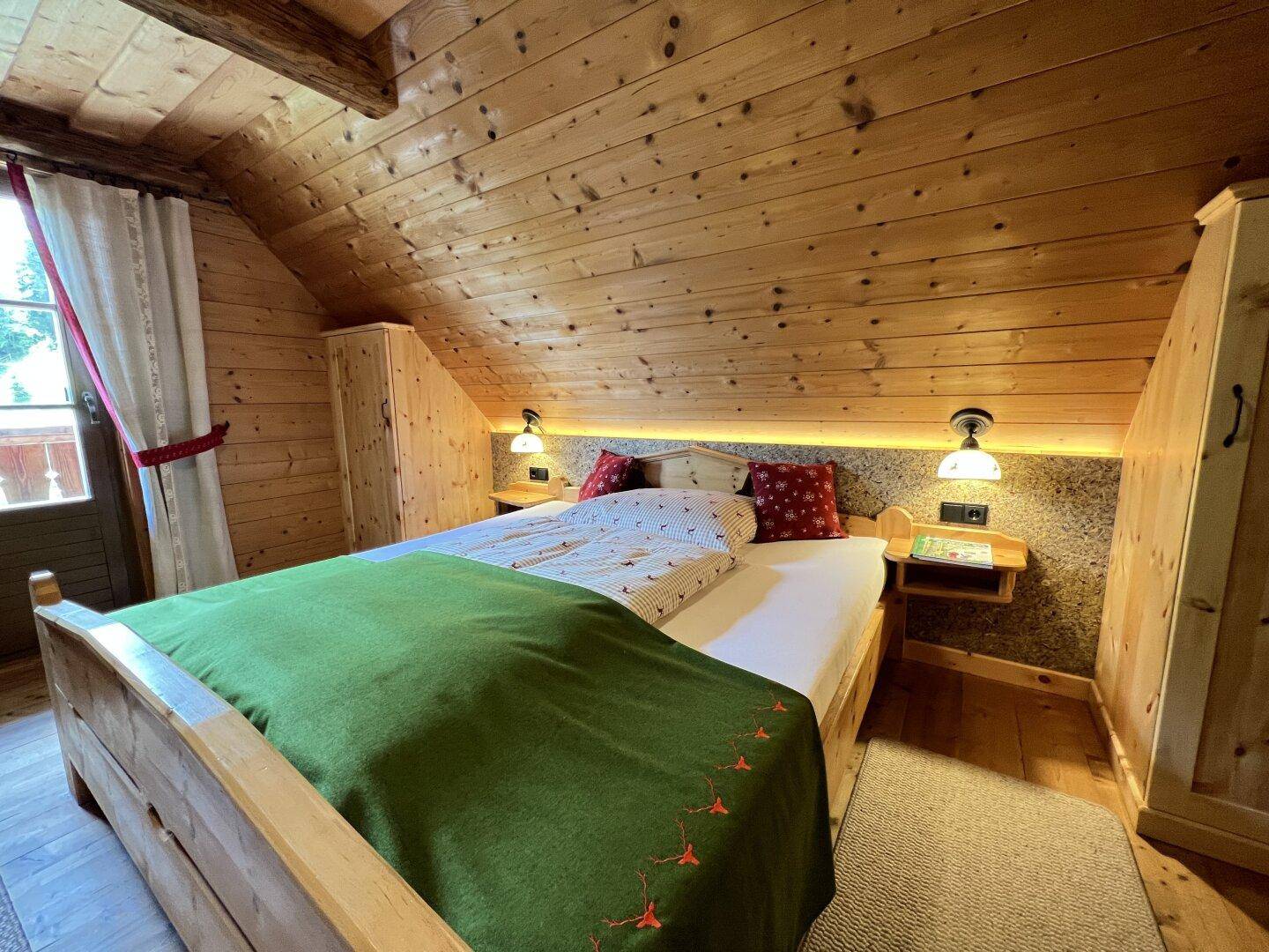 Helles Schlafzimmer mit Holzwänden, Doppelbett und integrierten Nachttischen unter Dachschrägen.