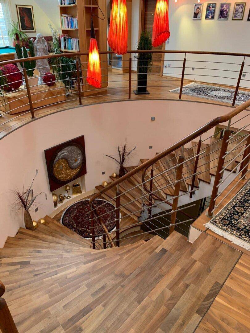 Beeindruckende Wendeltreppe aus Holz mit elegantem Geländer und dekorativen Hängelampen.