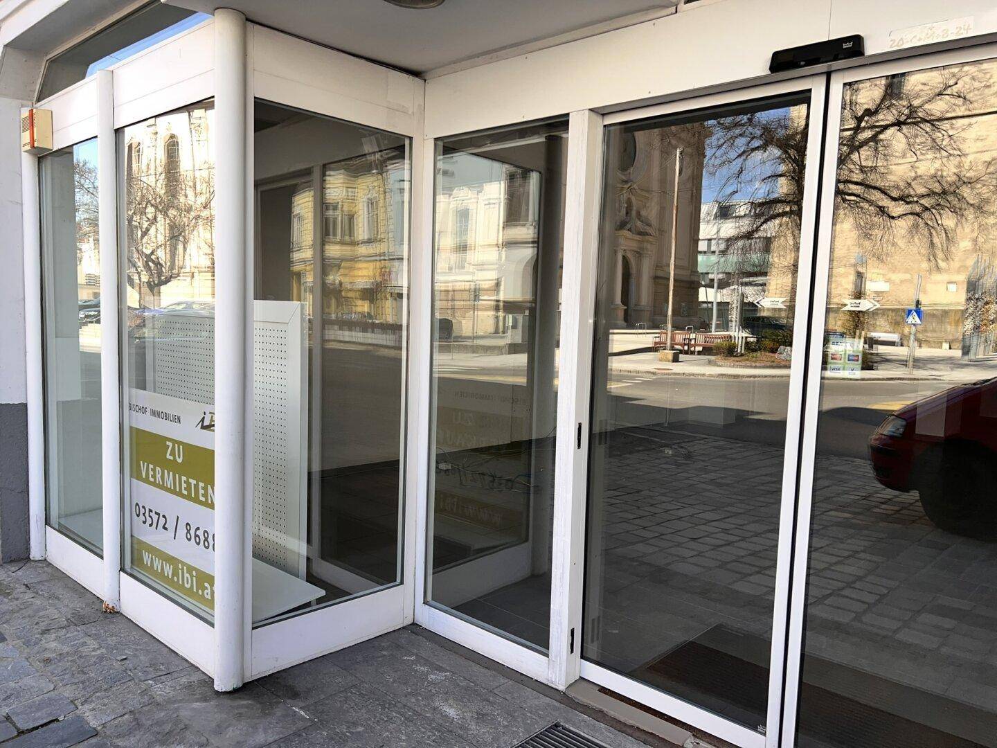 Moderner Eingangsbereich eines Geschäfts mit großen Glastüren und einem 'Zu Vermieten'-Schild.