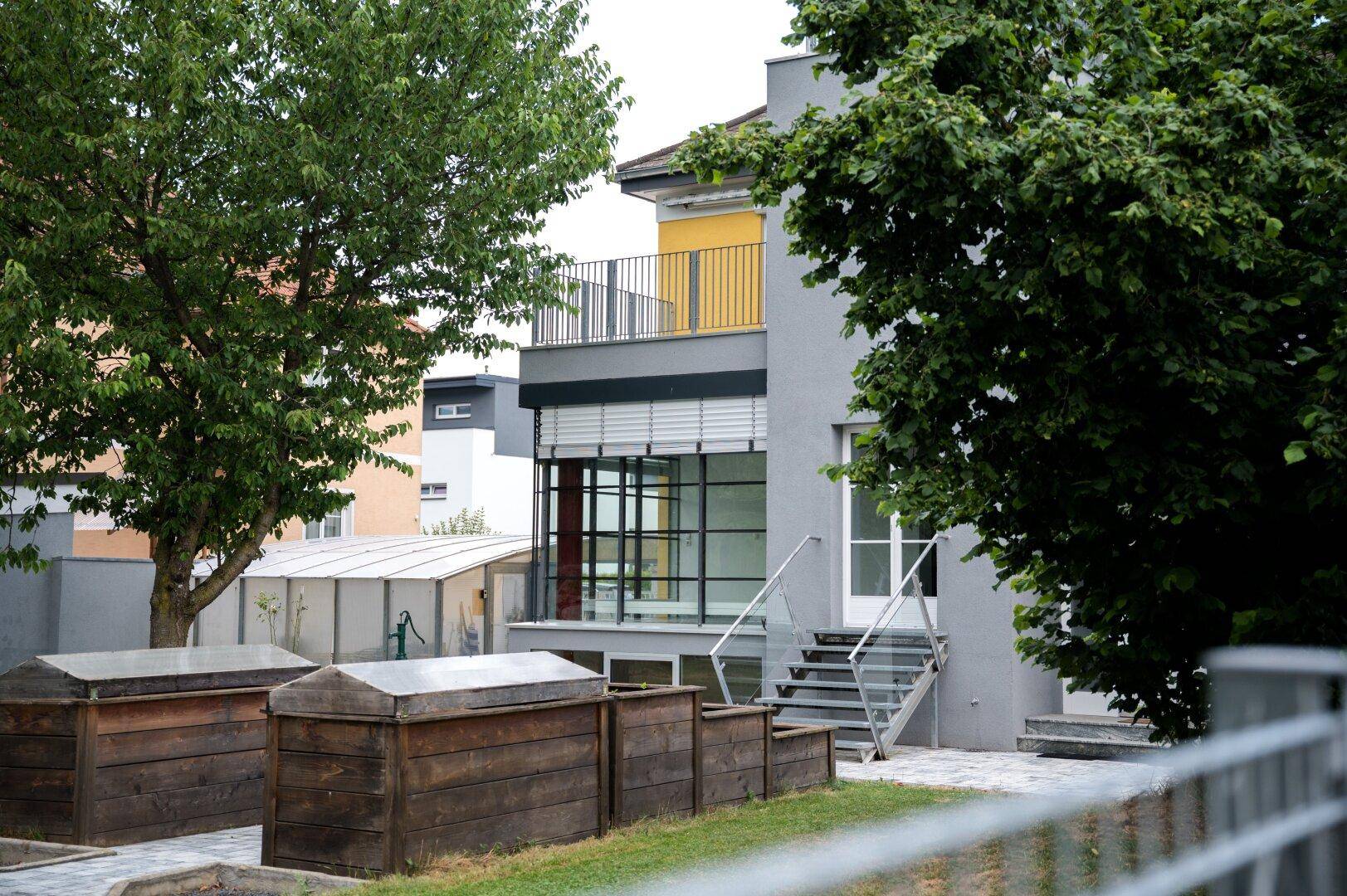 Ansicht des modernen Hauses mit großer Glasfassade und gelbem Balkon im oberen Bereich.