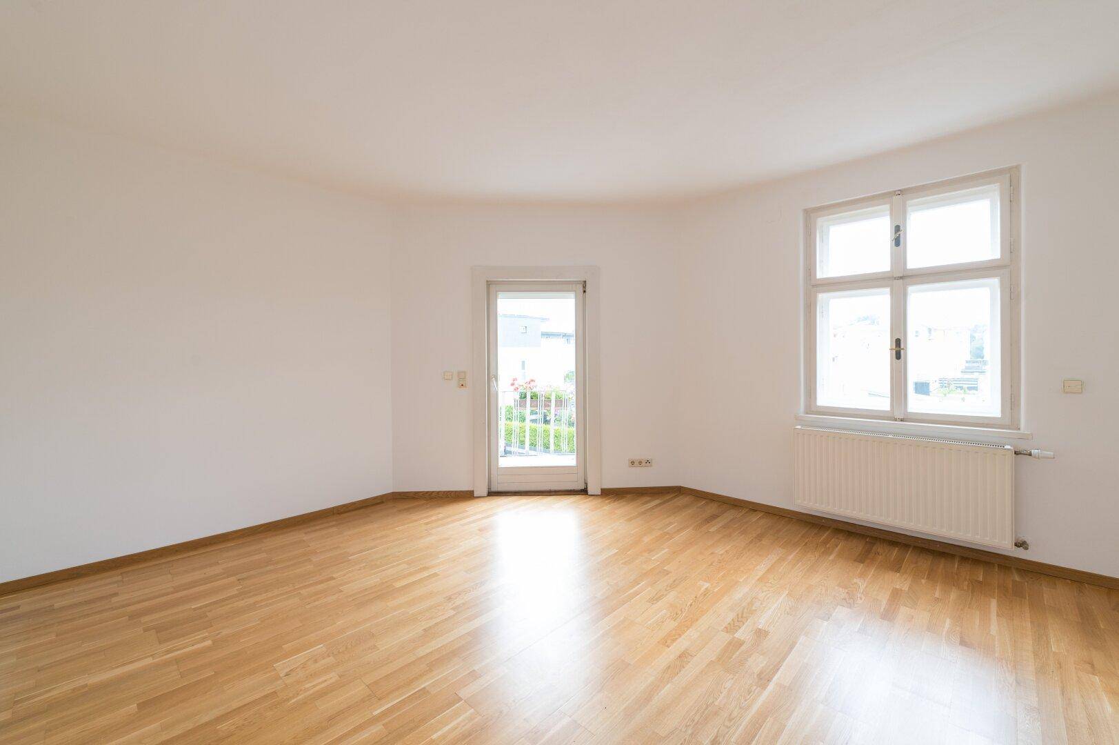 Heller Raum mit Holzboden und Zugang zu einem französischen Balkon.