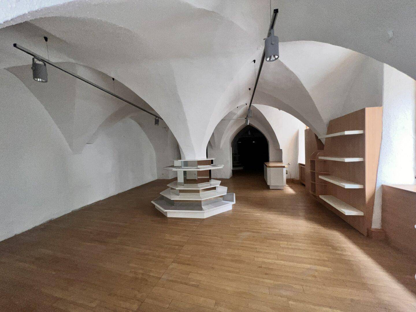 Heller Ladenraum mit eleganten Gewölbedecken, Holzboden und flexiblen Präsentationsmöbeln.