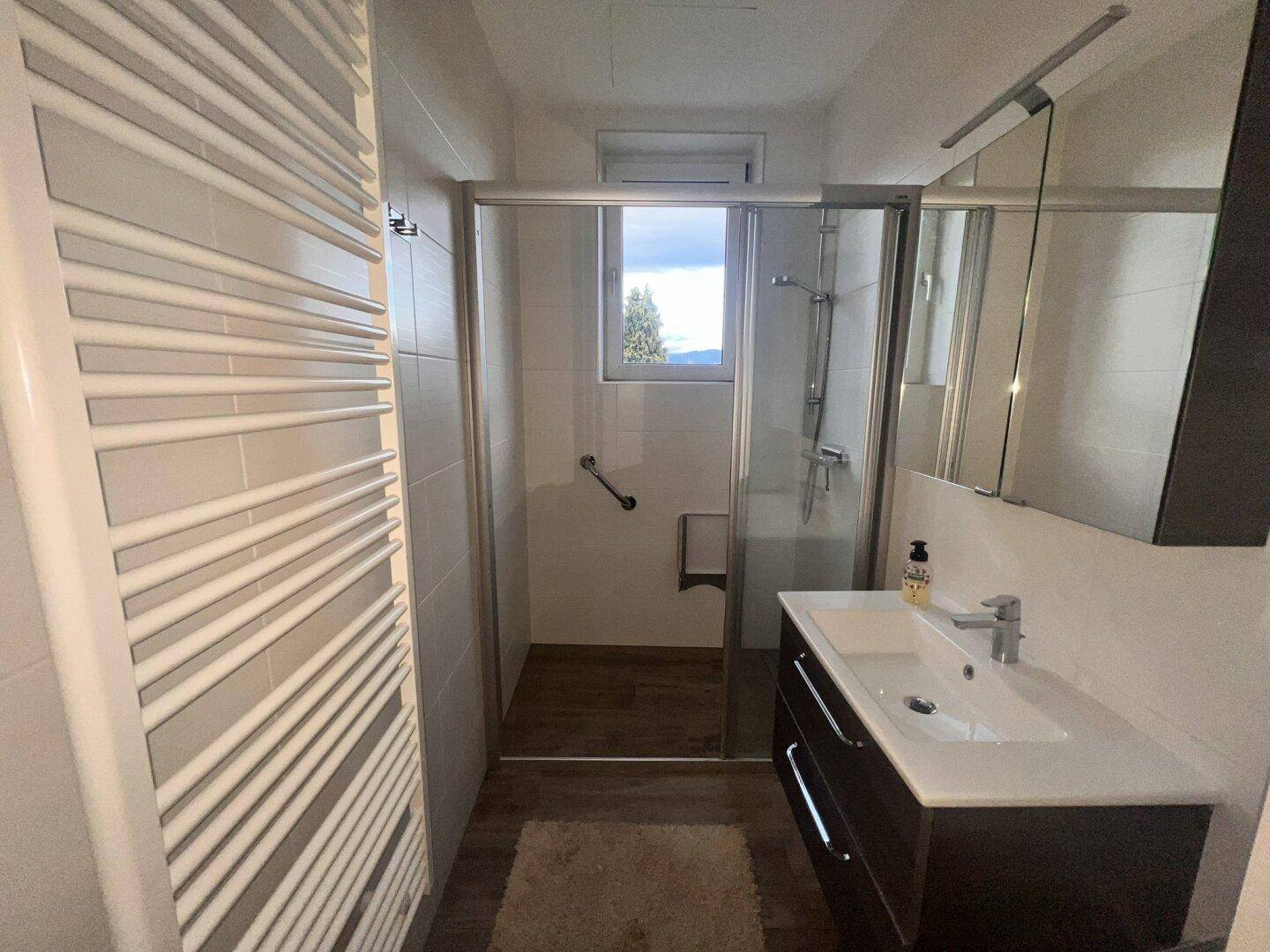 Modernes Badezimmer mit ebenerdiger Dusche, Waschtisch und beheiztem Handtuchhalter.
