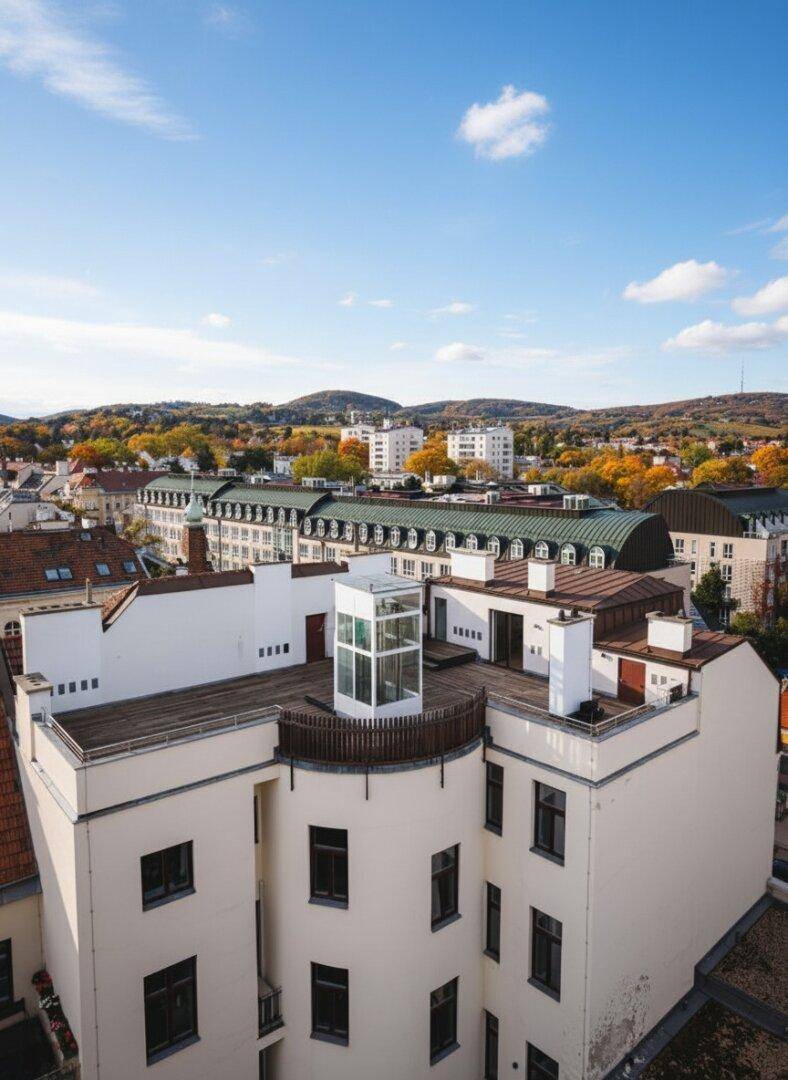 Panoramablick auf das Gebäude mit Dachterrasse und die umliegende Stadtlandschaft mit Hügeln.