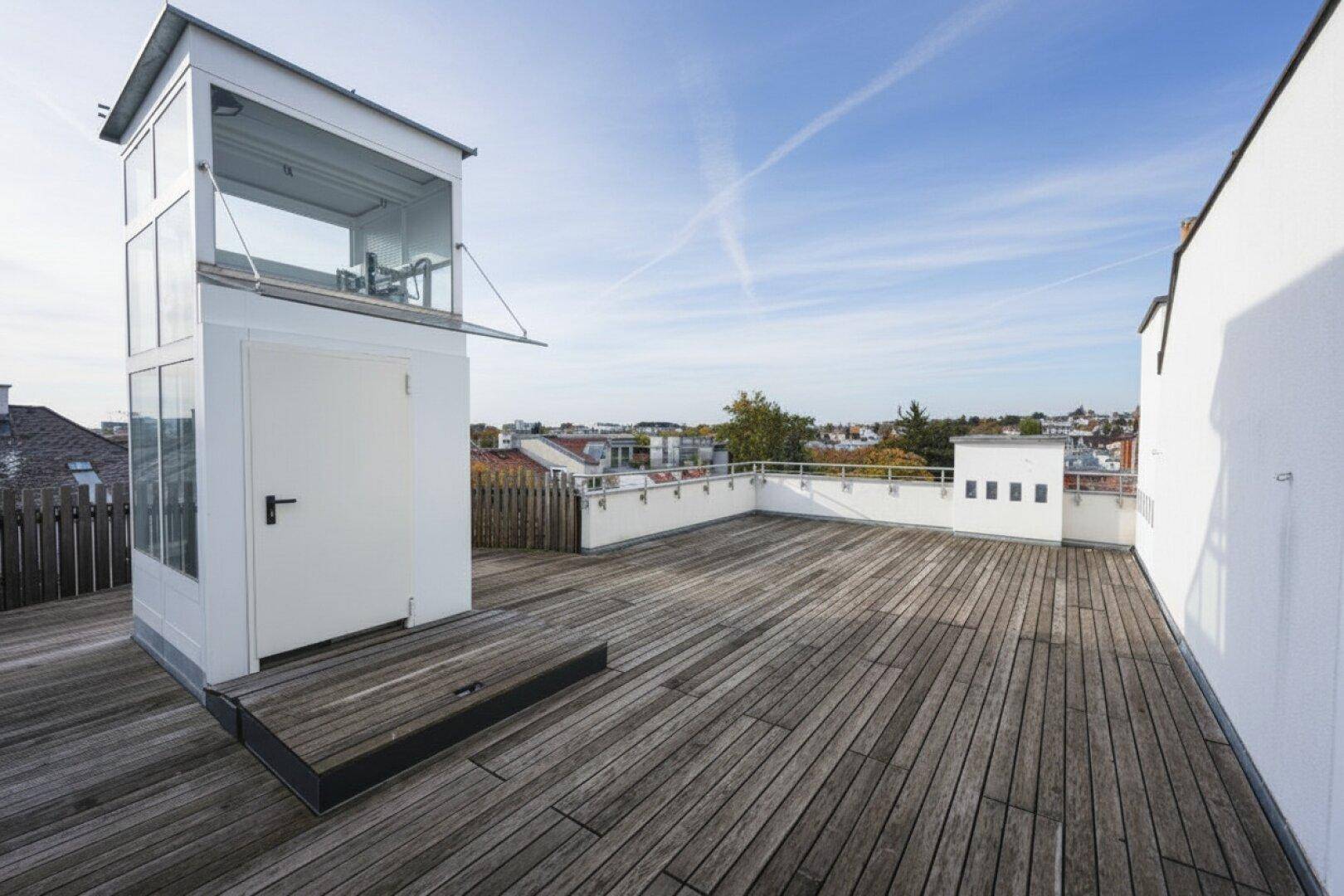 Geräumige Dachterrasse mit Holzboden und einem modernen Aufzug, der den Zugang erleichtert.