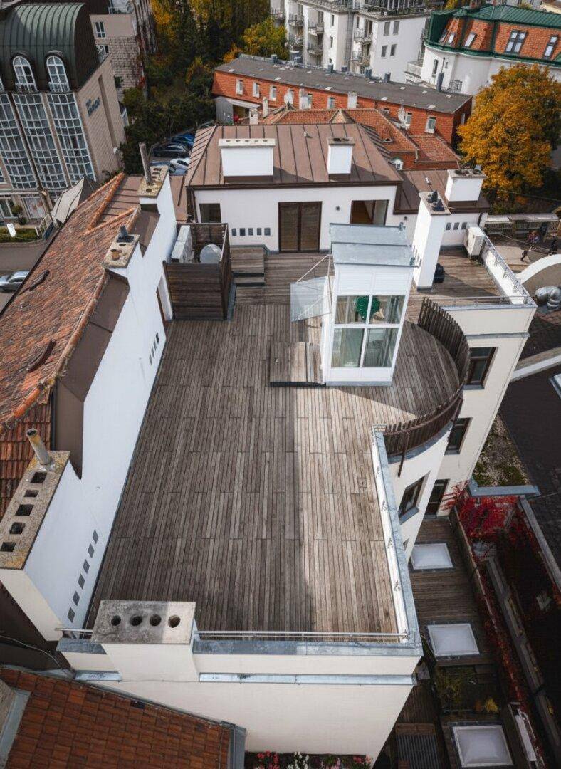 Weitläufige Dachterrasse mit Holzboden und einem gläsernen Aufzug für bequemen Zugang.