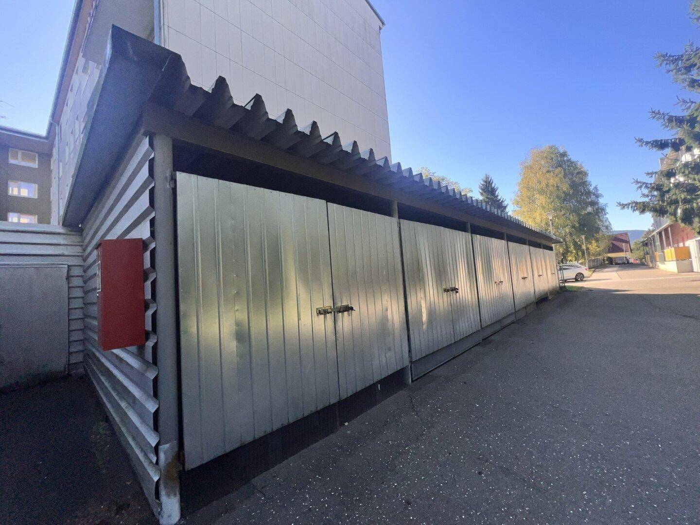 Lange Reihe von Garagenboxen aus Metall unter einem Wellblechdach.