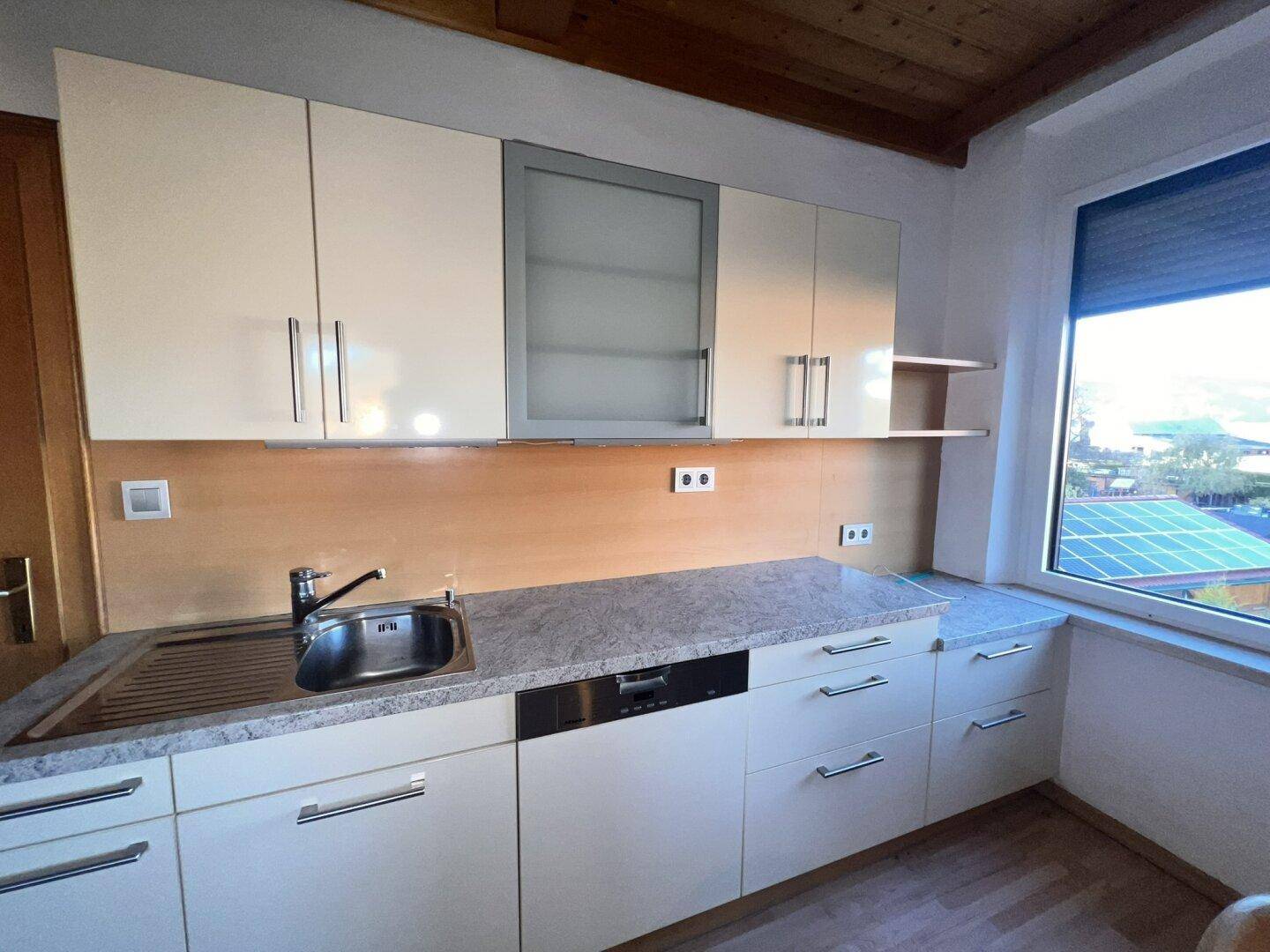 Funktionale Küche mit hellen Schränken, Spülmaschine und Fenster mit Weitblick.