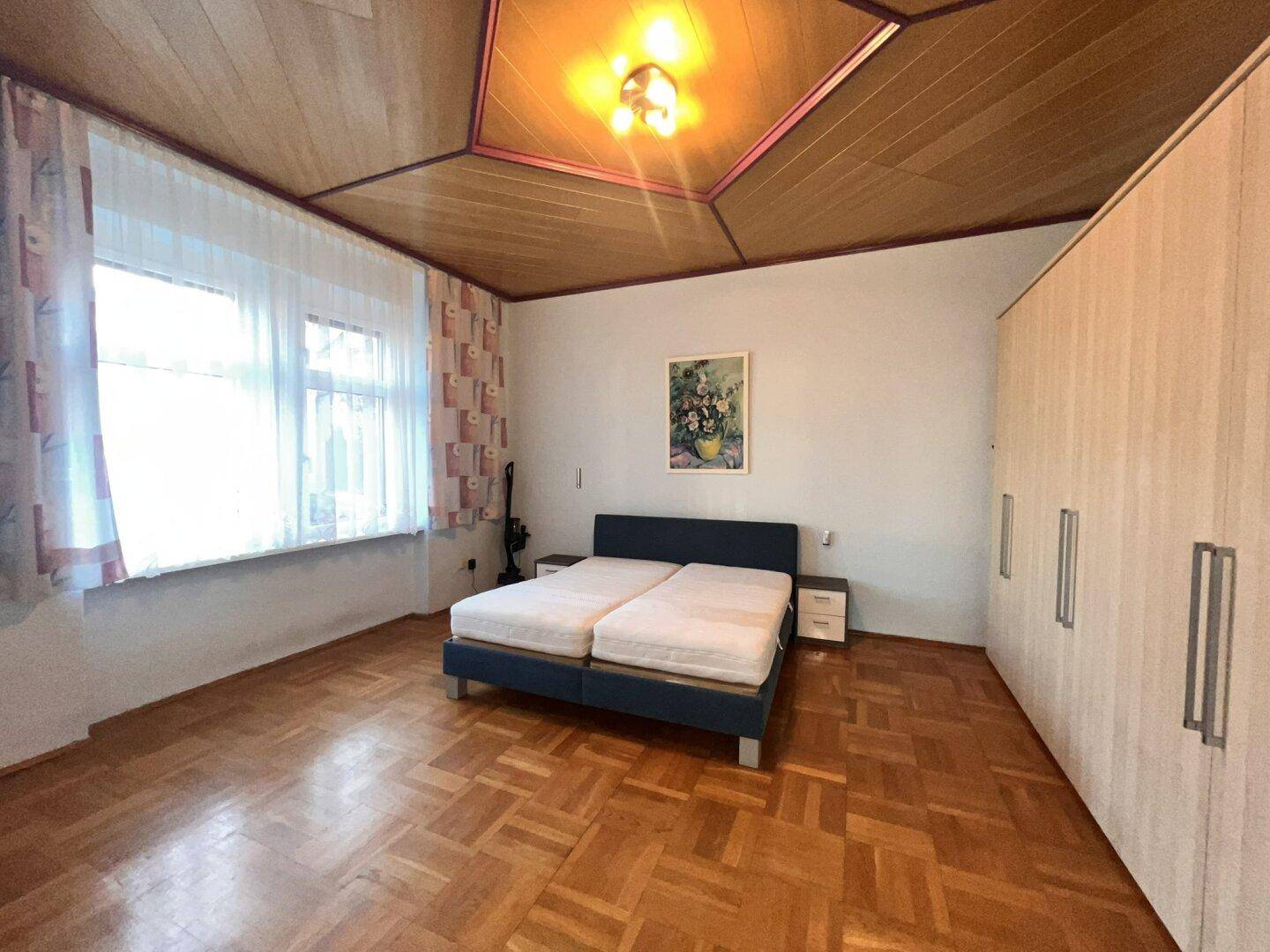 Geräumiges Schlafzimmer mit Parkettboden, Doppelbett und großem Kleiderschrank.