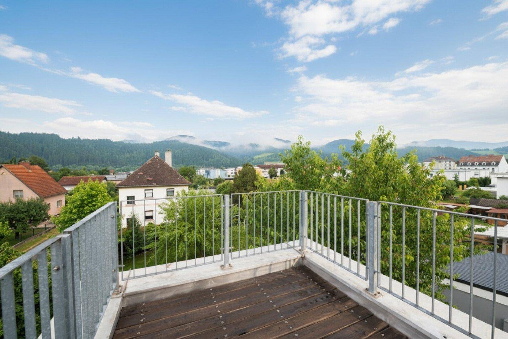 Dachterrasse mit Holzboden und Metallgeländer bietet einen weiten Blick auf die Umgebung.