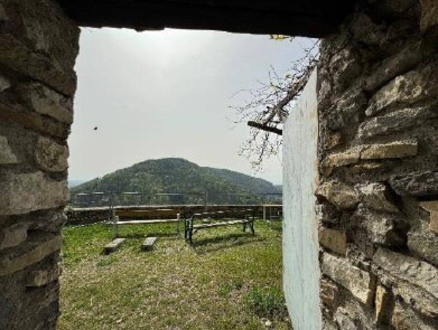 Ein kleiner Gartenbereich innerhalb der Burgmauern mit Bänken und Blick auf die umliegende Landschaft.