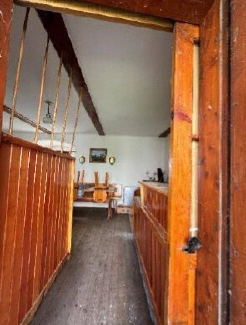 Rustikaler Essbereich mit Holztäfelung, Holzbalken und Tischen mit umgedrehten Stühlen.