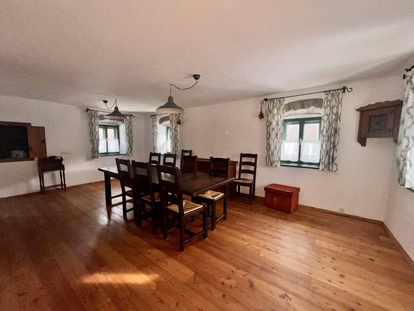 Geräumiger Essbereich mit Holzdielenboden, großem Holztisch und traditionellen Fenstern.
