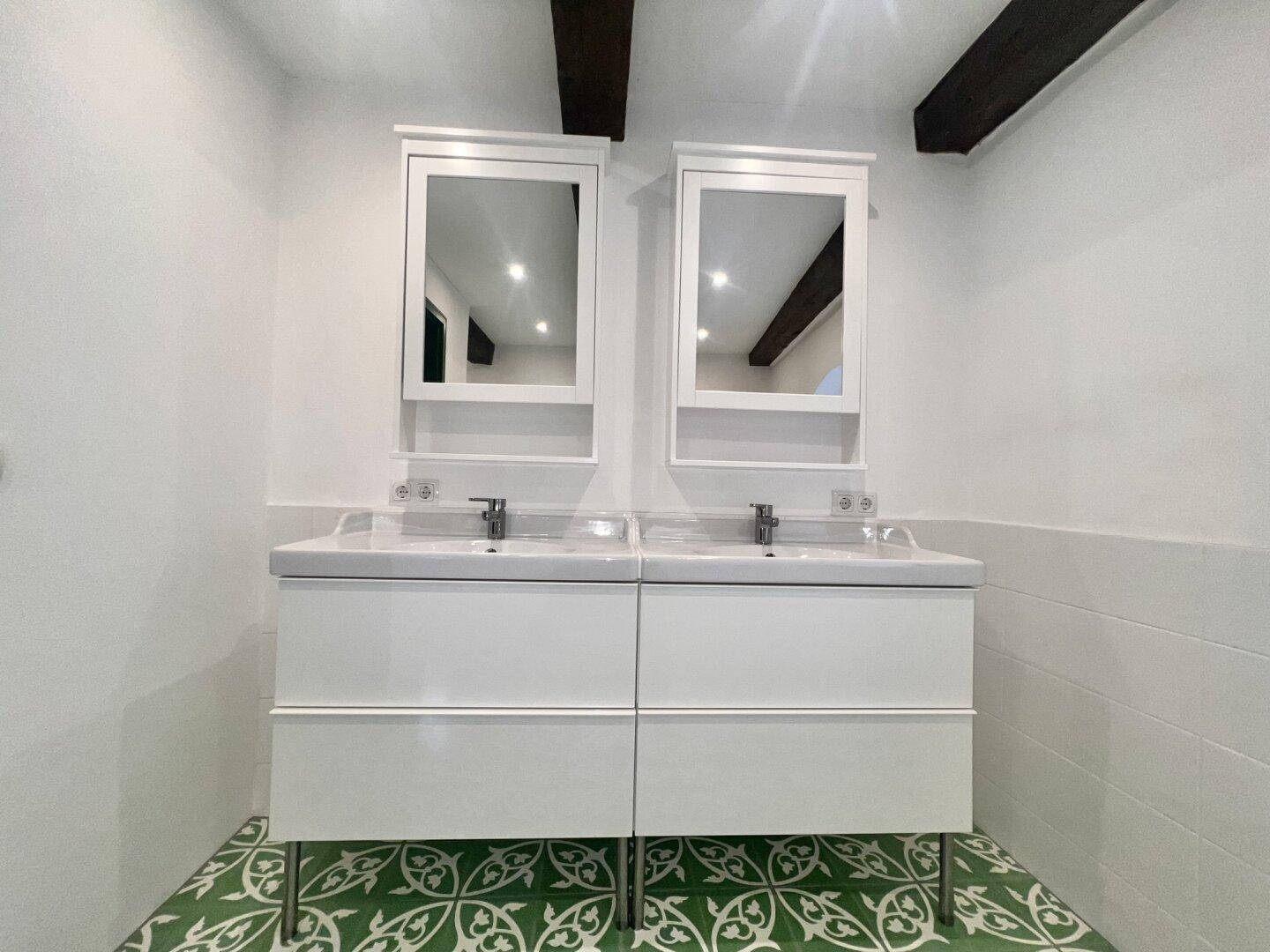 Doppelwaschbecken mit modernen Unterschränken und Spiegelschränken im Badezimmer.