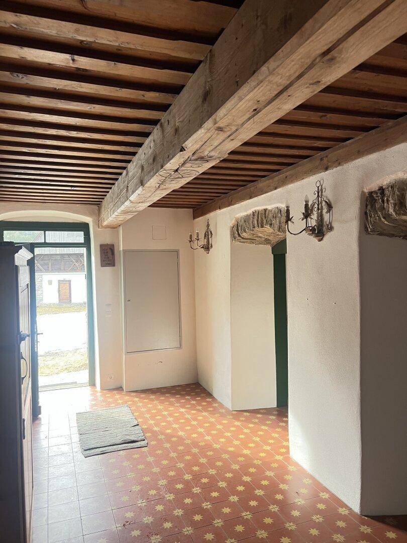 Eingangsbereich mit rustikalen Holzbalken, Terrakottafliesen und traditionellen Wandleuchten.