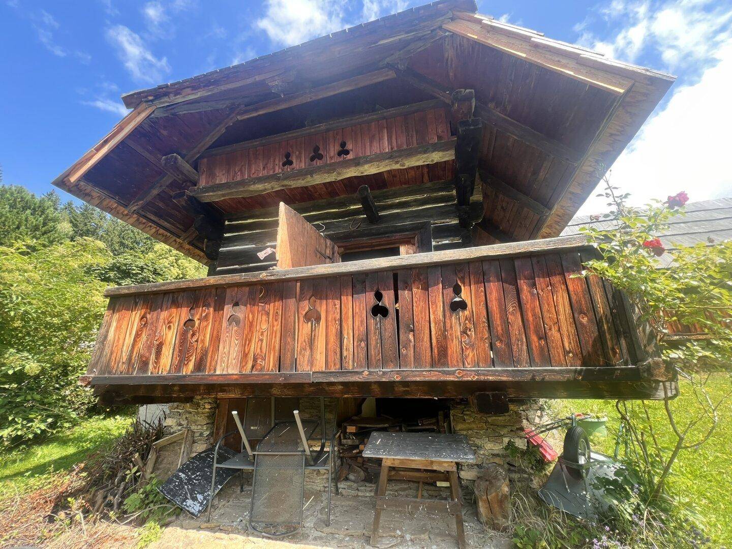 Detailansicht eines rustikalen Holzchalets mit traditionellem Balkon und geschnitzten Verzierungen.