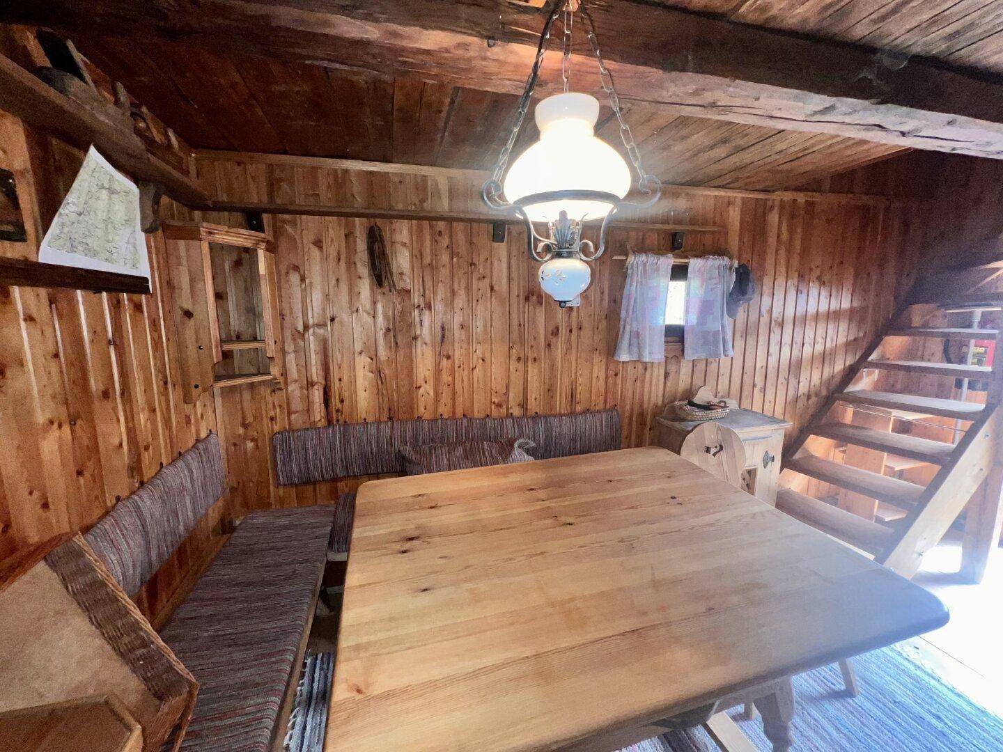 Rustikaler Wohn- und Essbereich mit Holztäfelung, großem Holztisch und traditioneller Beleuchtung.