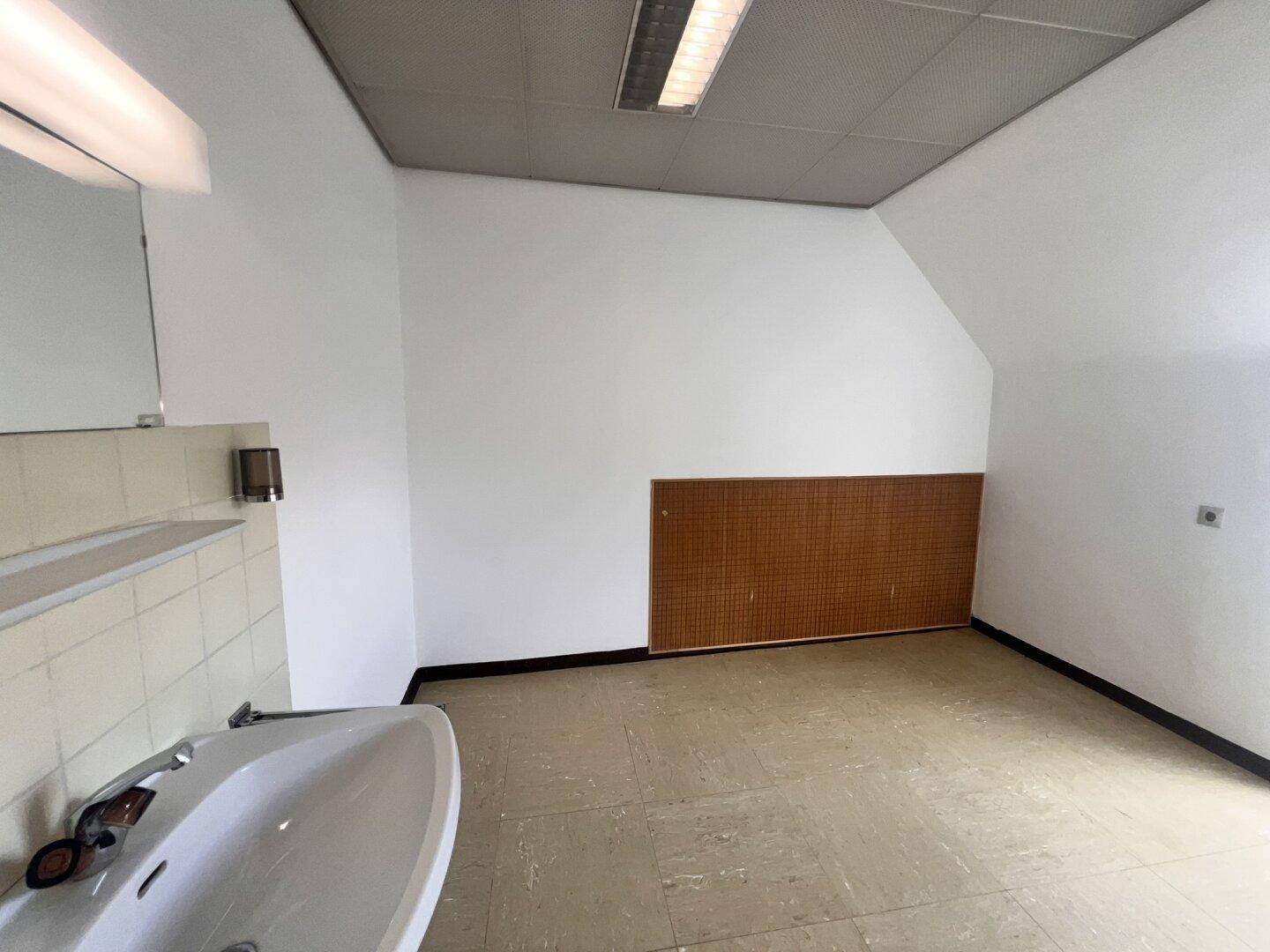 Funktionaler Raum mit Waschbecken, Fliesen und Holzverkleidung, ideal als Nebenraum oder Waschküche.