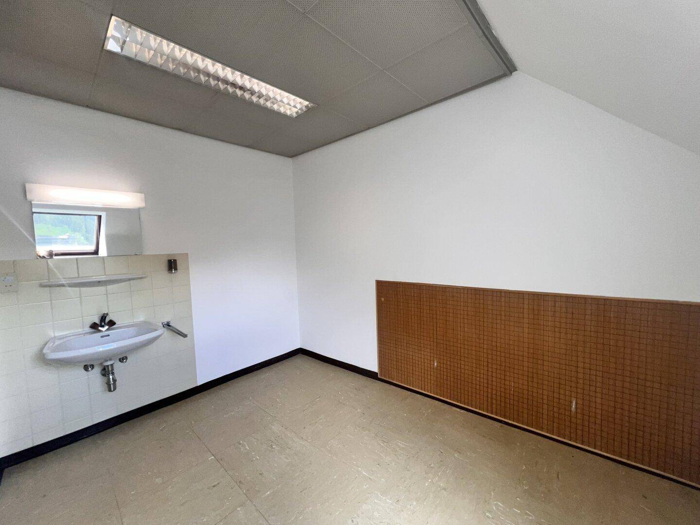 Heller Nebenraum mit Waschbecken, Spiegelschrank und kleinem Fenster, ausgestattet mit Holzverkleidung.