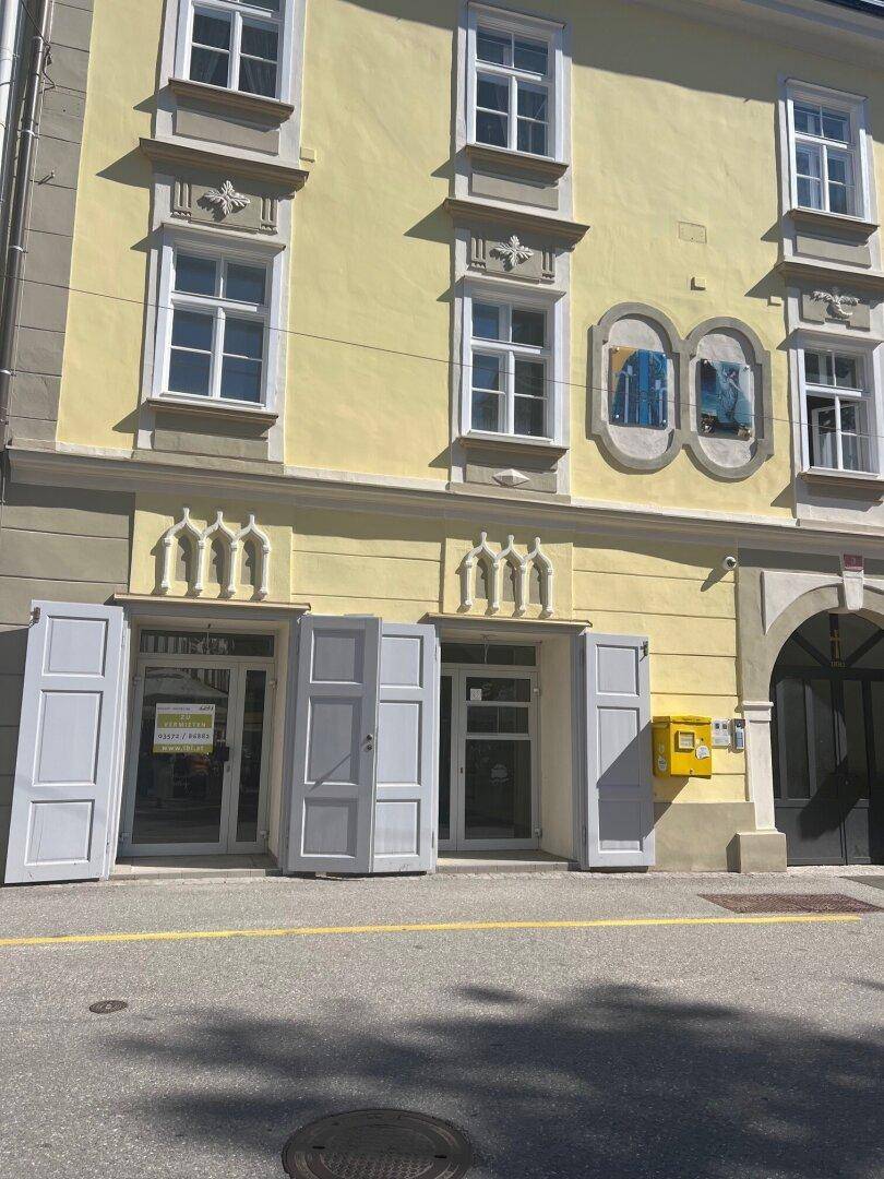 Historische Fassade eines Gebäudes mit Fensterläden und dekorativen Elementen.