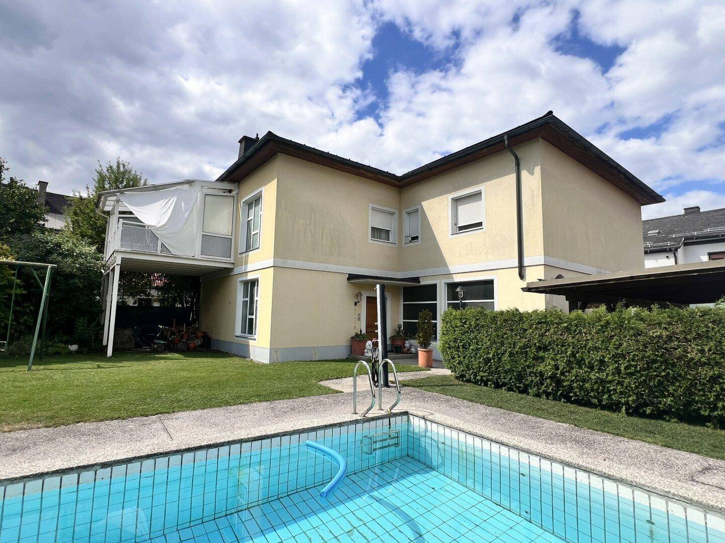 Blick auf das Haus mit Pool und Garten, umgeben von viel Grün.