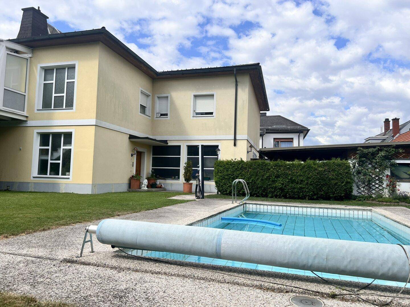 Ansicht des Hauses vom Garten aus mit Swimmingpool und gepflegter Hecke.