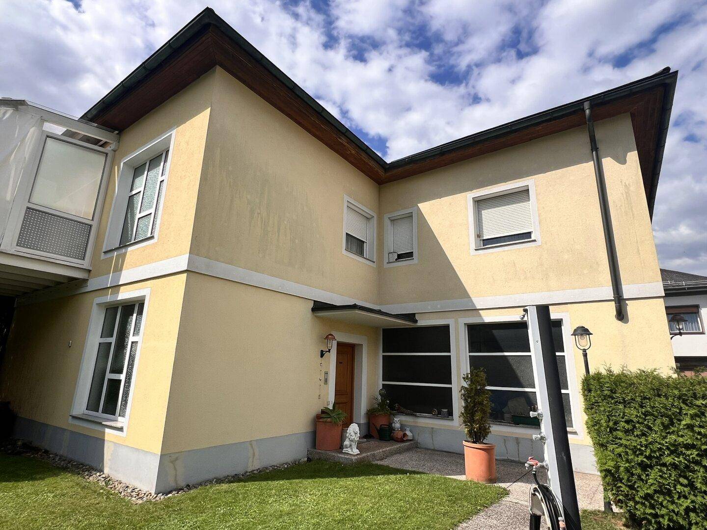 Seitenansicht des Wohnhauses mit gelber Fassade und großen Fenstern.