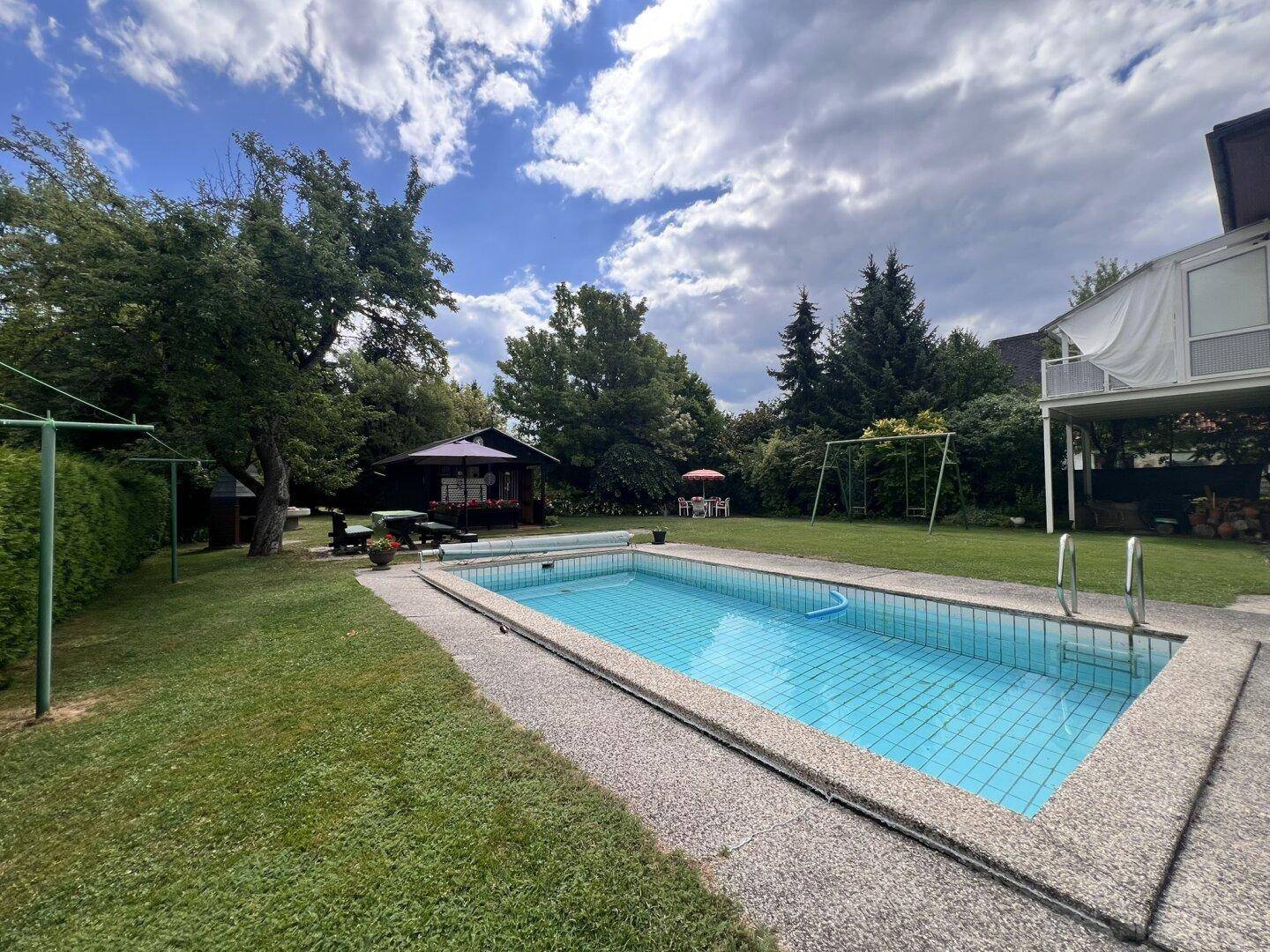 Großer Gartenbereich mit Swimmingpool, Rasen und einem charmanten Gartenhaus im Hintergrund.