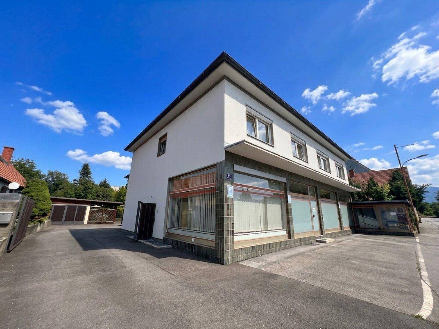 Eckansicht eines Geschäftsgebäudes mit großen Fenstern und Zugang zum Parkplatz.