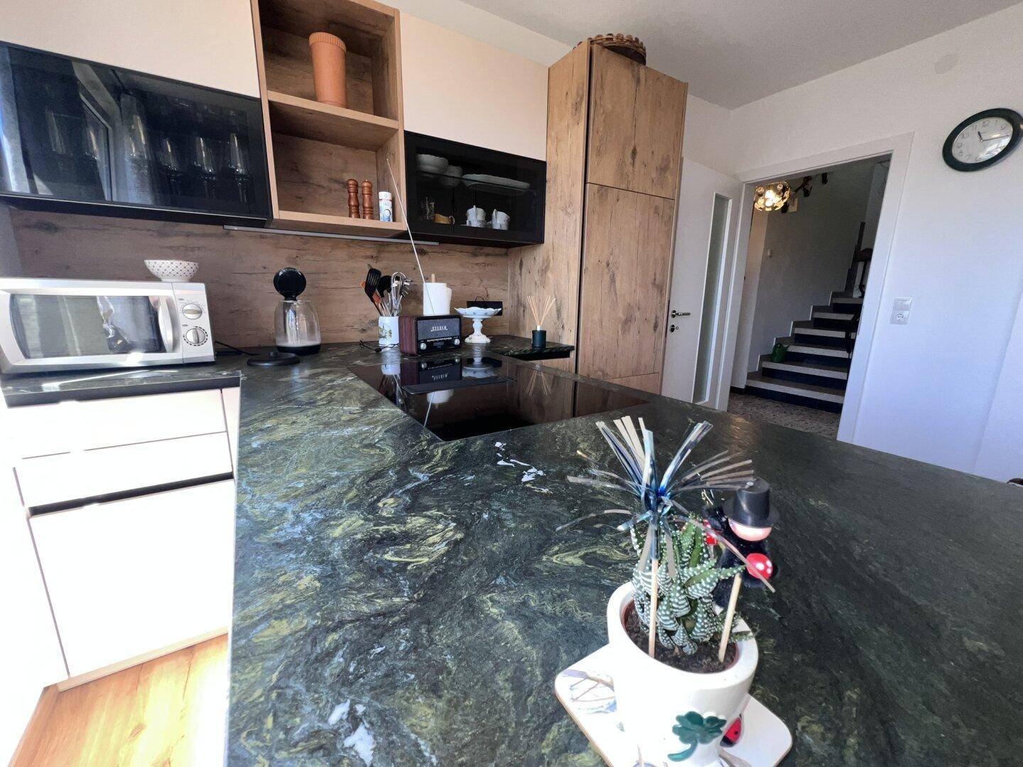 Detailansicht der Kücheninsel mit dunkler Naturstein-Arbeitsplatte und integriertem Induktionskochfeld.