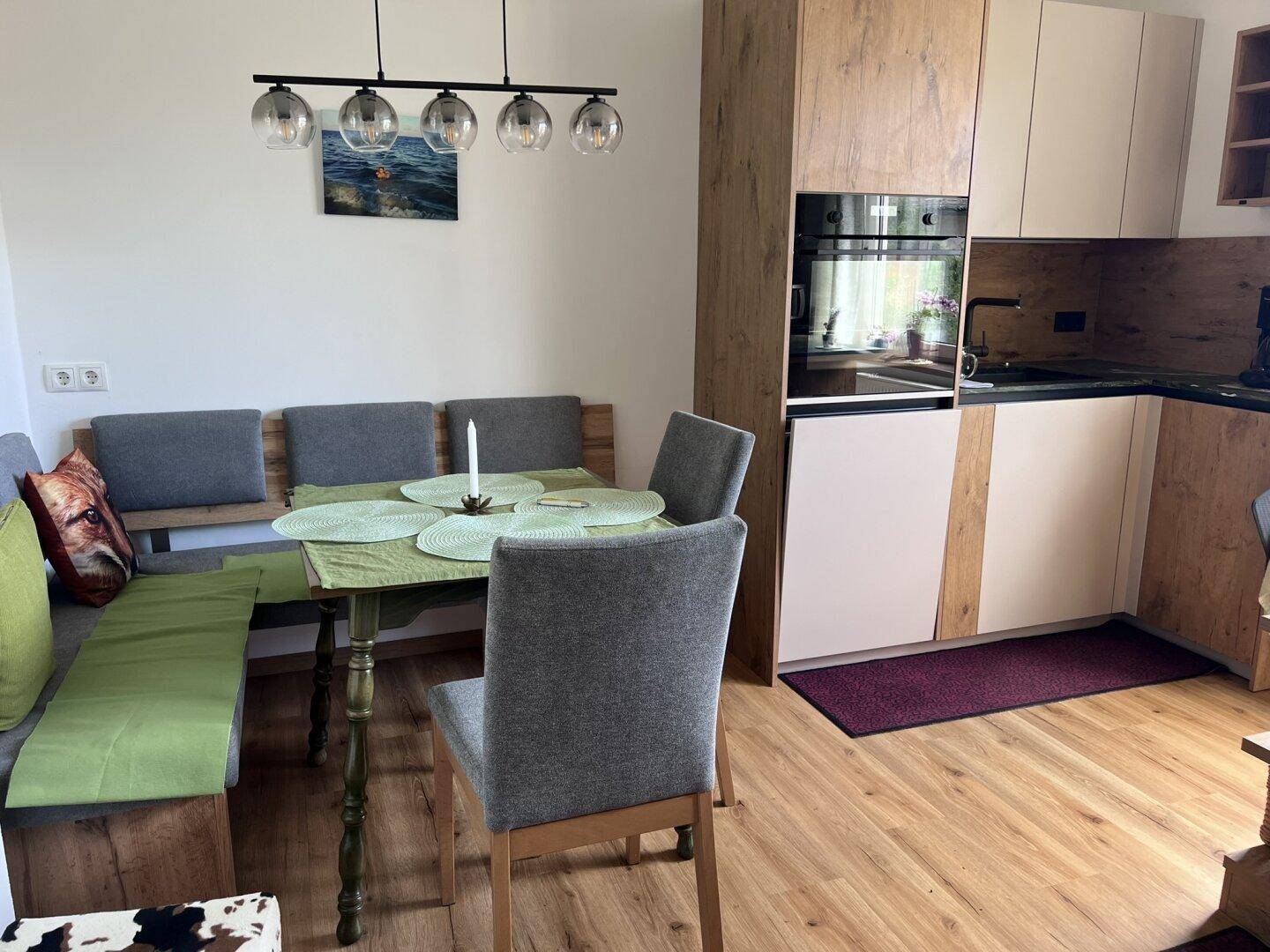 Moderne offene Küche mit Holzelementen und Essbereich mit Eckbank und stilvoller Pendelleuchte.