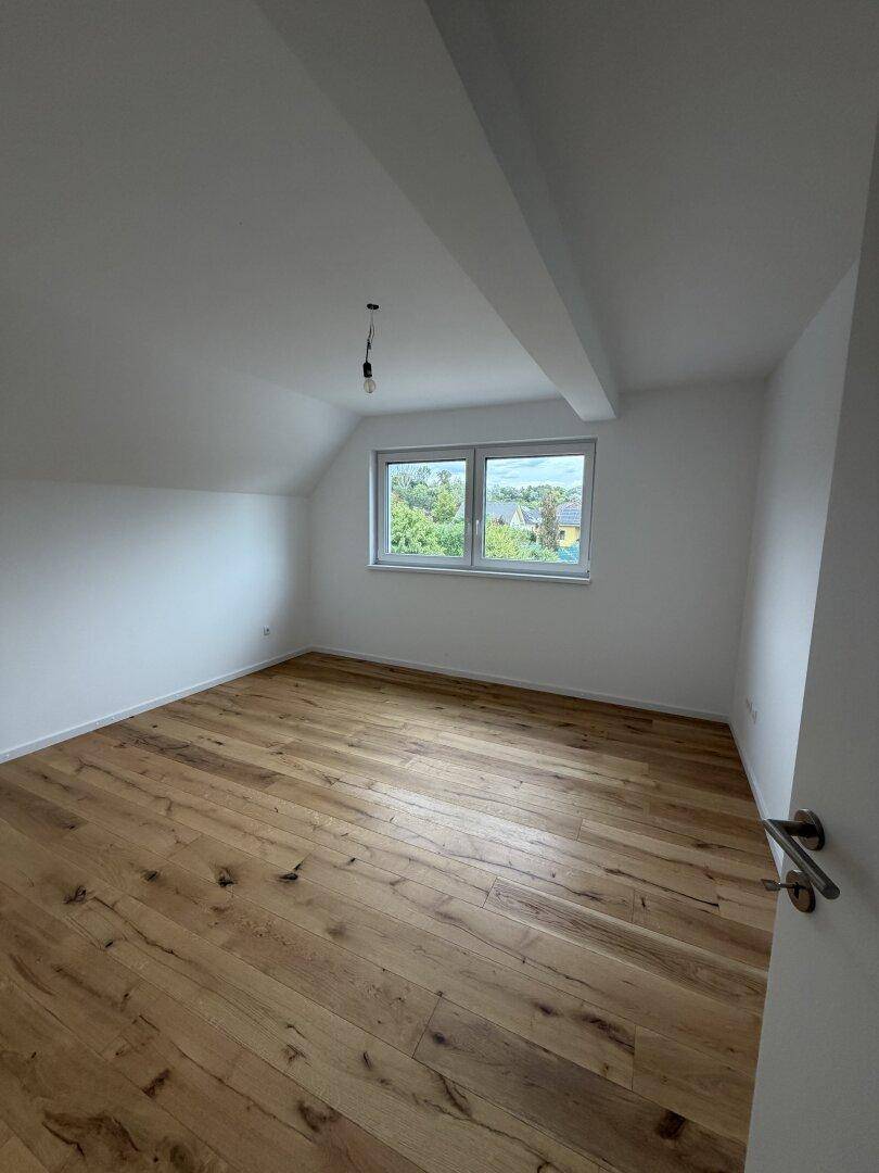 Gemütliches Schlafzimmer im Dachgeschoss mit Holzdielenboden und schrägen Wänden.