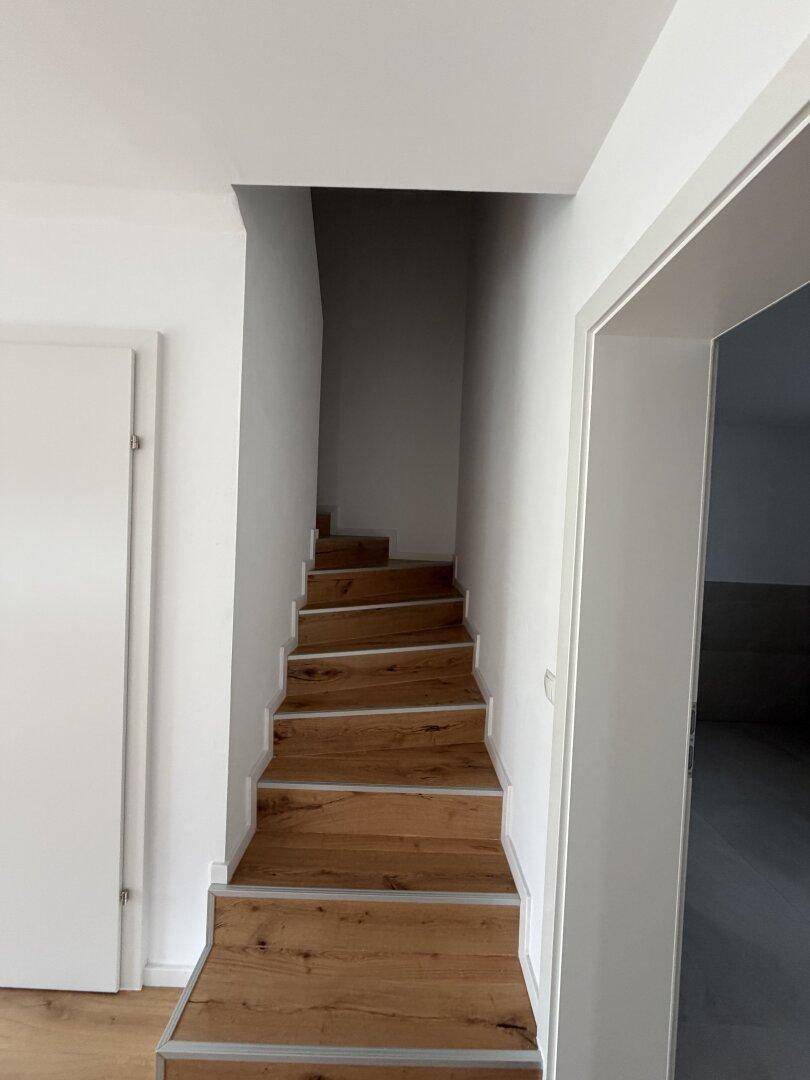 Moderne Holztreppe mit Metallkanten, die die verschiedenen Etagen des Hauses verbindet.