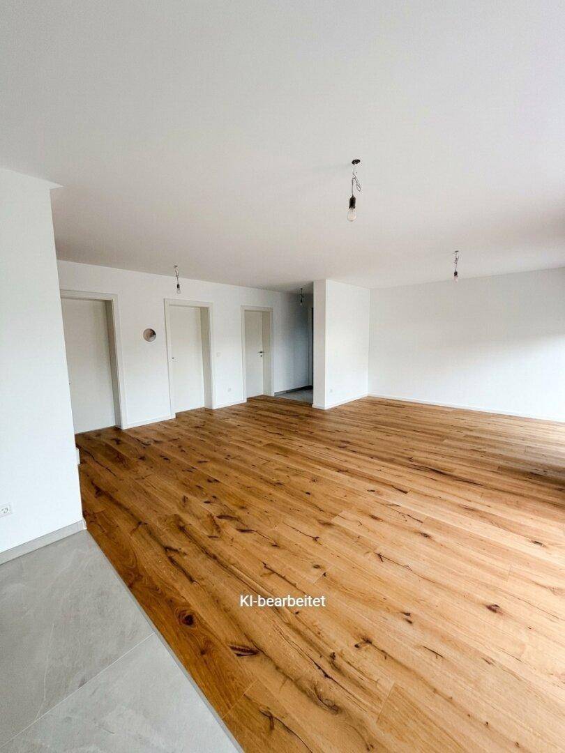 Geräumiger, heller Raum mit Holzdielenboden und angrenzendem Fliesenbereich, bereit zum Einzug.