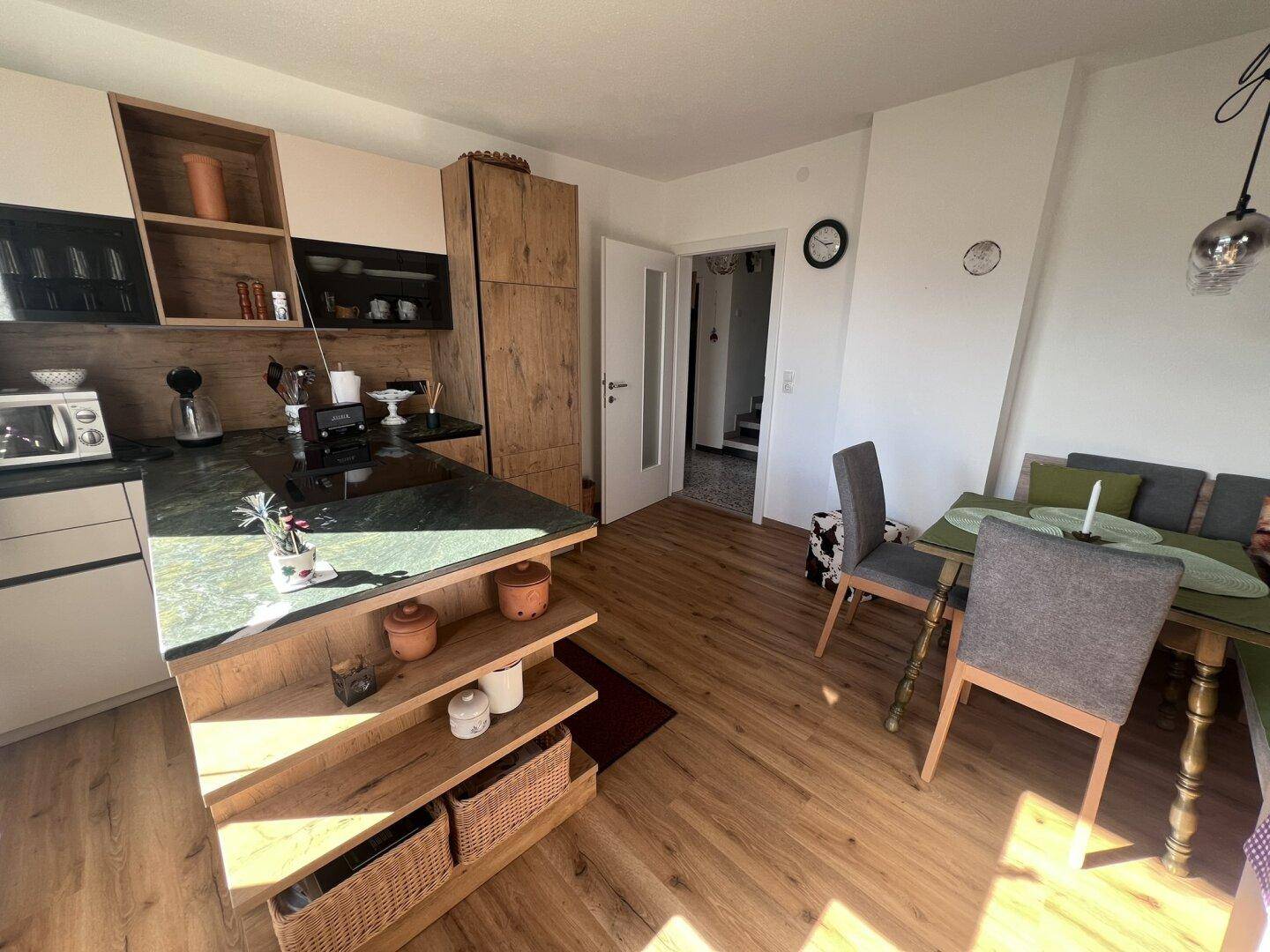 Moderne Wohnküche mit Holzfronten, Kücheninsel und Essbereich mit Holzboden.