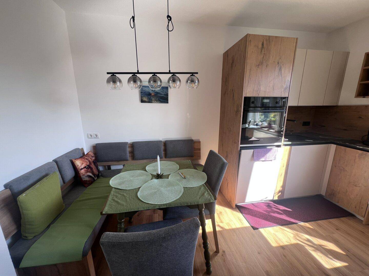 Gemütlicher Essbereich in der Küche mit Eckbank, Holztisch und moderner Pendelleuchte.