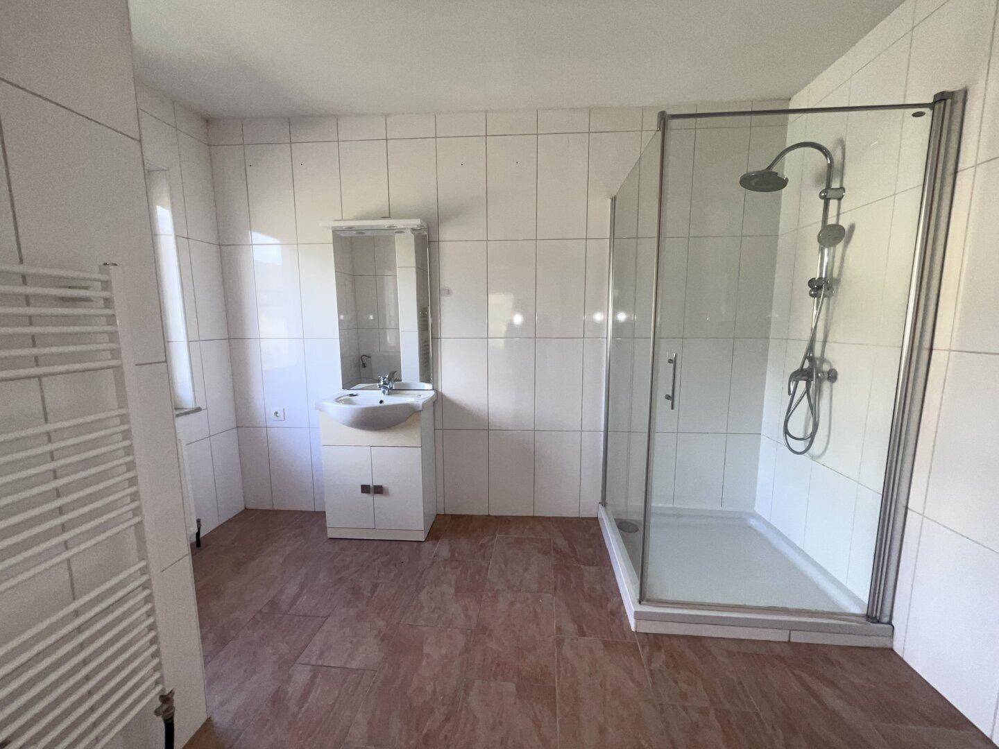 Modernes Badezimmer mit Duschkabine, Waschbecken und weiß gefliesten Wänden.