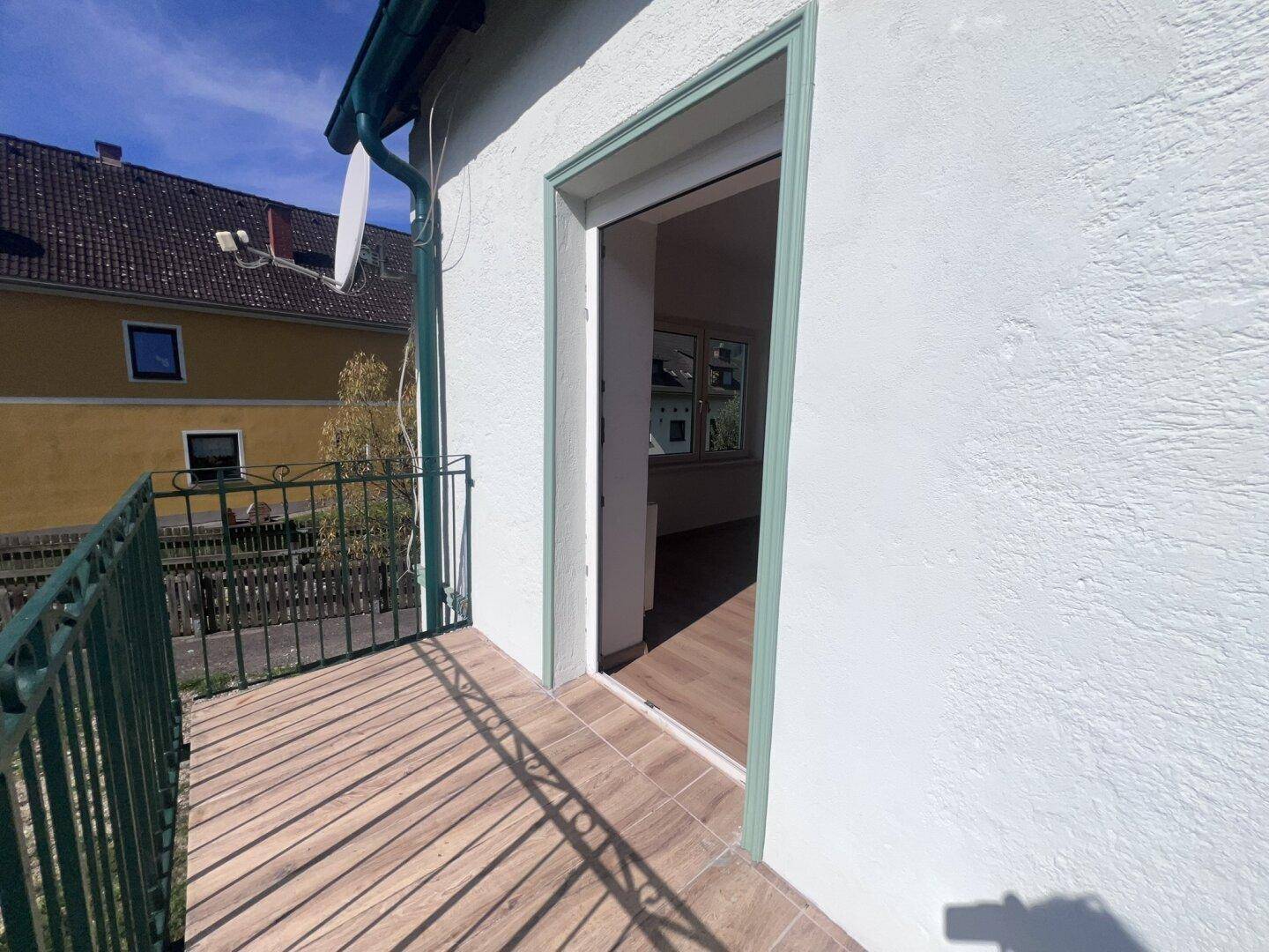Kleiner Balkon mit Fliesenboden und Metallgeländer, zugänglich vom Innenraum.