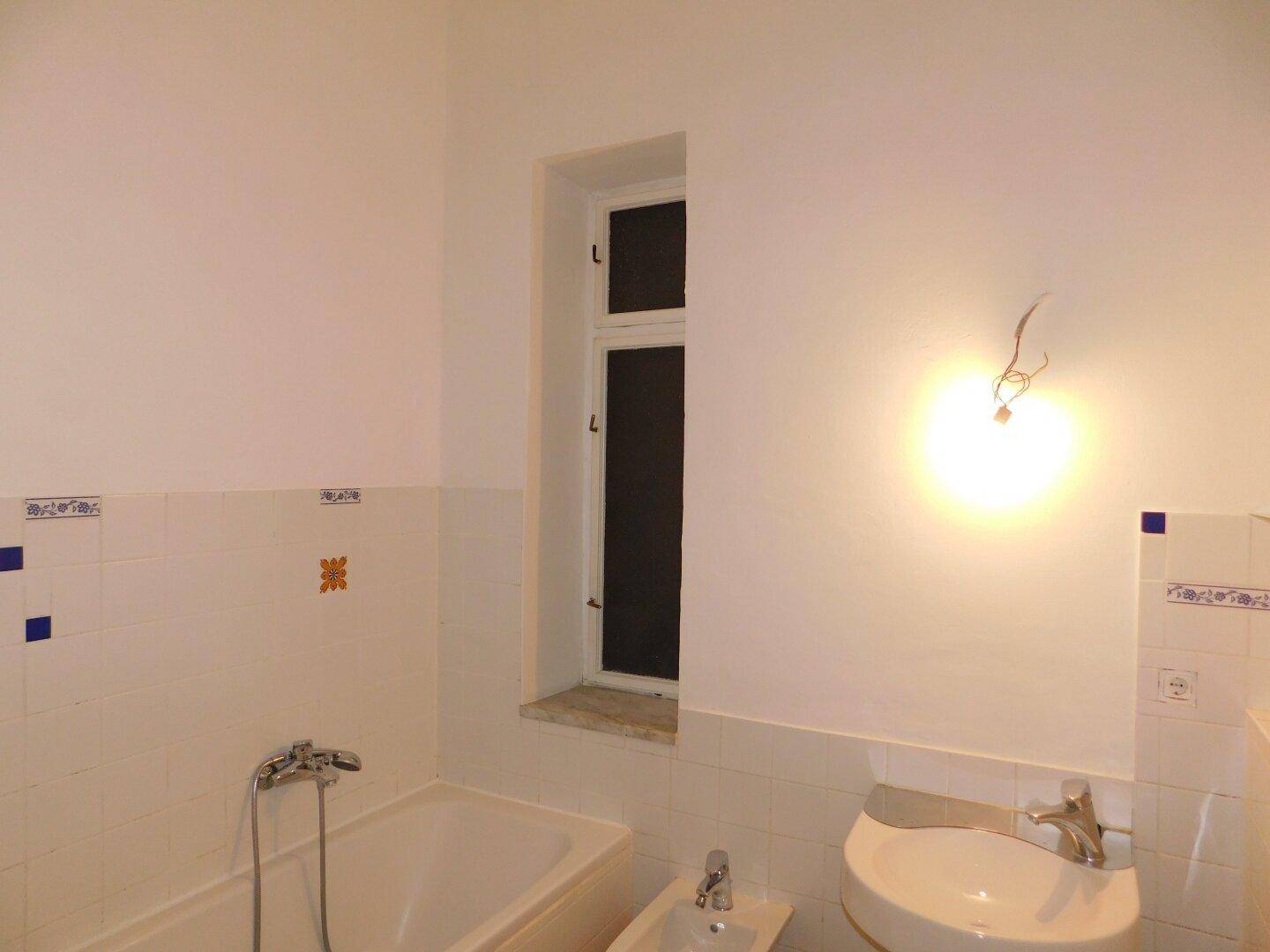Badezimmer mit Badewanne, Waschbecken, Bidet und einem Fenster, in klassischem Stil gefliest.