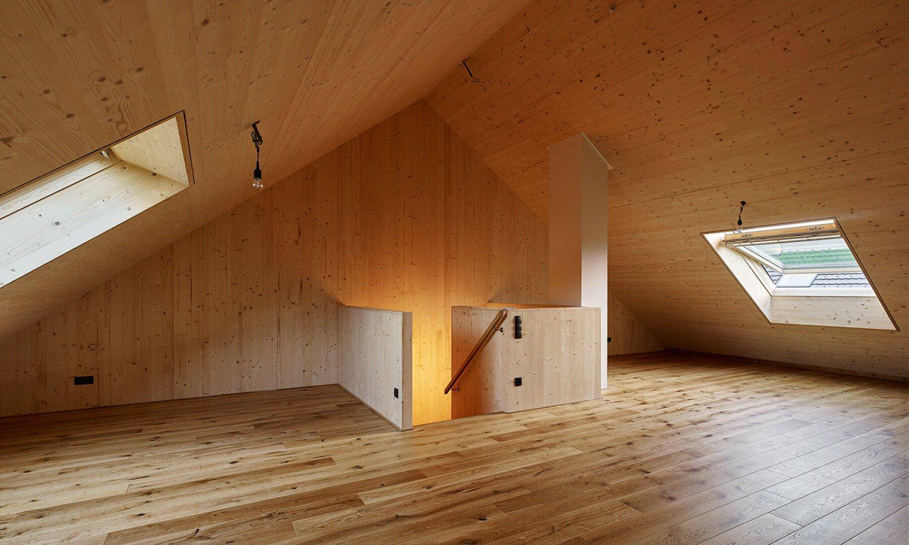 Geräumiger Dachbodenraum mit Holzboden, schrägen Decken und mehreren Dachfenstern für viel Licht.